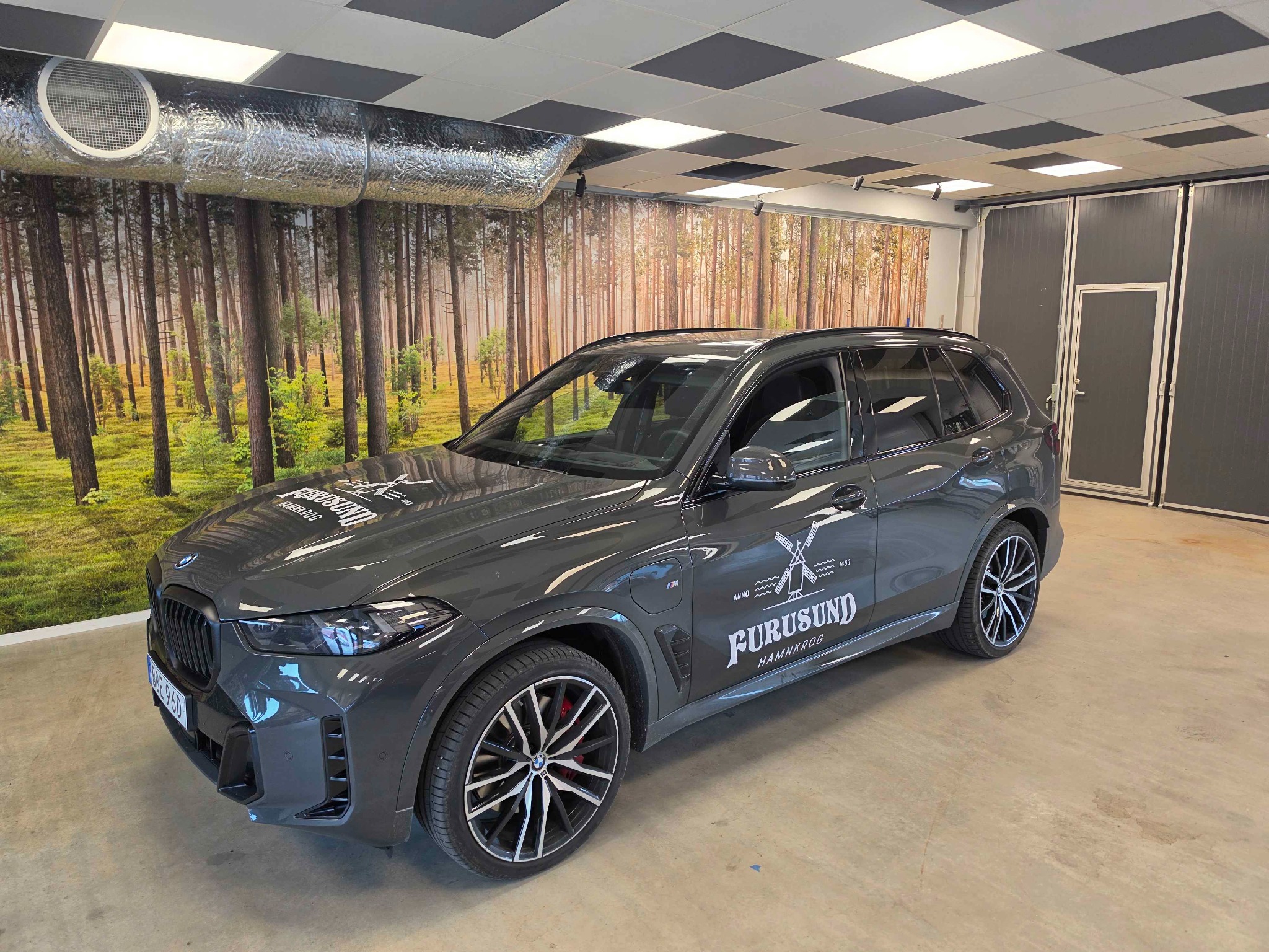 Grå BMW med vita dekaler för Furusund Hamnkrog på motorhuv och bildörr
